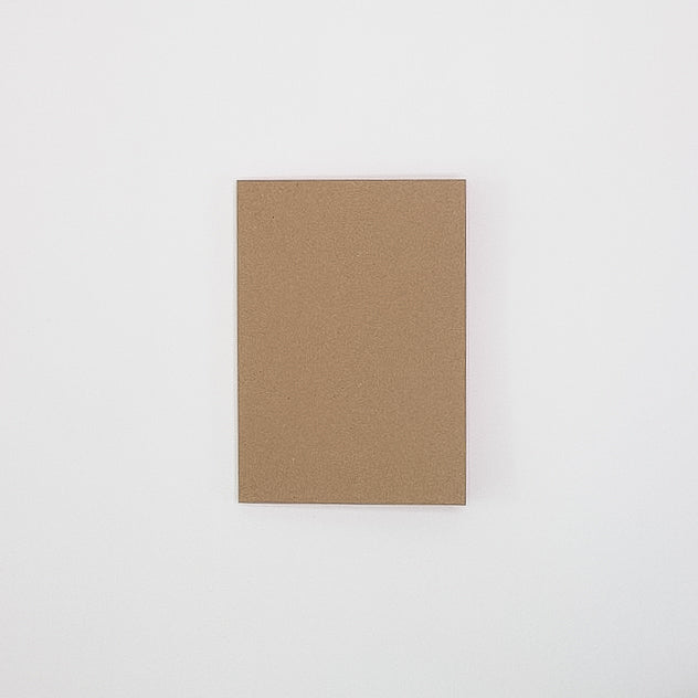 A closed A5 Kraft cover notebook laying flat on a white background. 